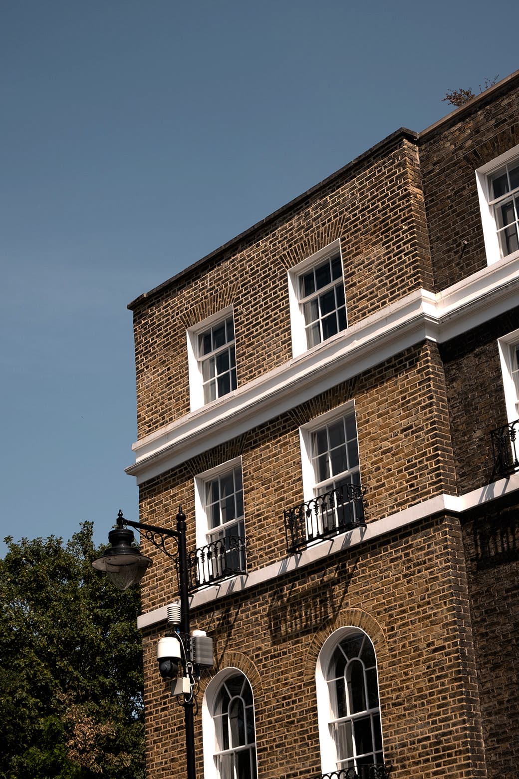 A Georgian brick building in Angel, London, with white sash windows and iron balconies against a blue sky