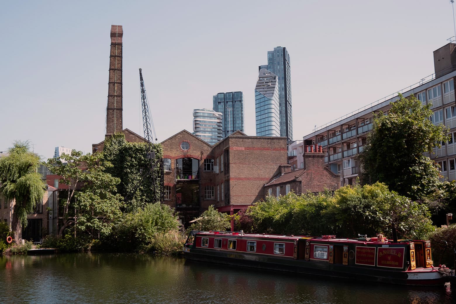 A red narrowboat moored on the canal at Angel, Islington, with converted warehouses and City tower blocks behind
