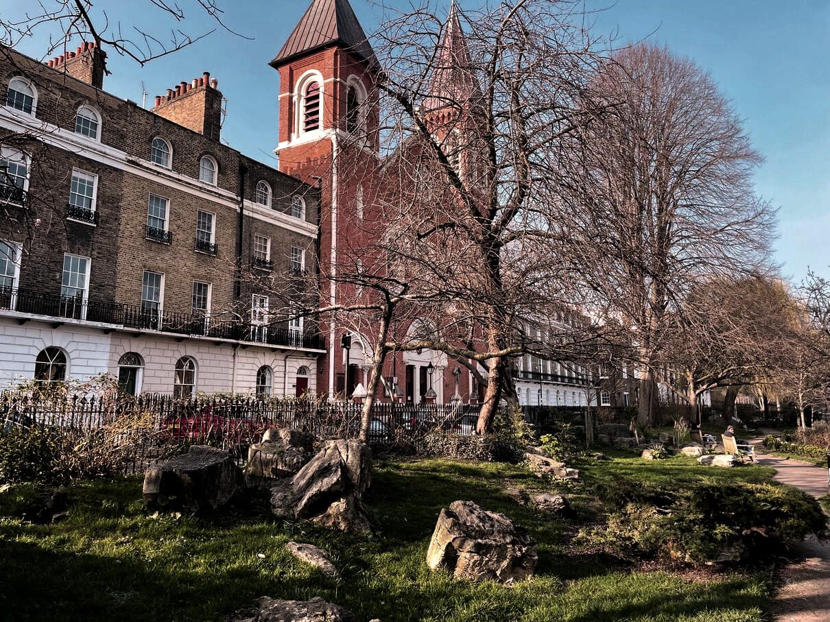 Georgian terraced houses and a red-brick church tower behind a small London garden